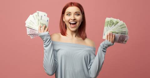 Een lachende jonge vrouw met bankbiljetten in haar hand